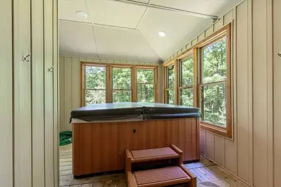 a room with a large soaking tub in a room with windows at Woodland Cabin Getaway in Greentown