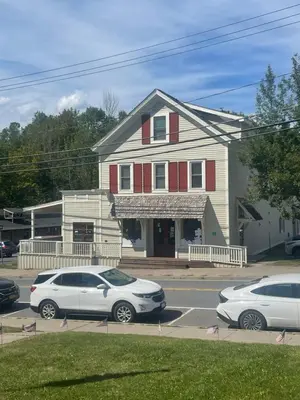 two cars parked in a parking lot in front of a house at The Innwoods - Two Bedroom Apartment in Tannersville