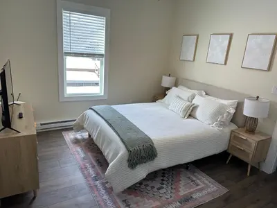 a white bedroom with a large bed and a window at The Innwoods - Two Bedroom Apartment in Tannersville