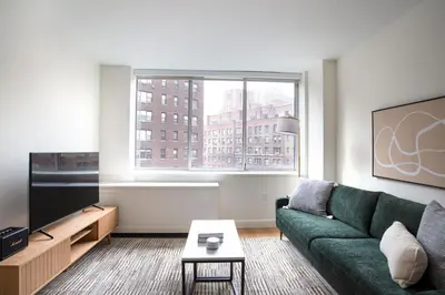 a living room with a green couch and a large window at Blueground Midtown E gym wd nr UN NYC-1150 in New York