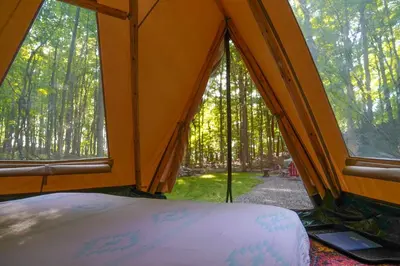 a tent with a bed and a view of trees at Lenape at Moon Valley Campground in Vernon Township