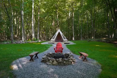a fire pit with two benches and a tent at Lenape at Moon Valley Campground in Vernon Township