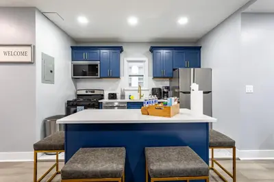 a kitchen with blue cabinets and a counter with stools at Comfort Meets Style 3BR Plus Parking in New Rochelle
