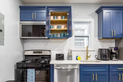 a kitchen with blue cabinets and a stove at Comfort Meets Style 3BR Plus Parking in New Rochelle