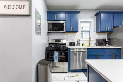 a kitchen with blue cabinets and a stove at Comfort Meets Style 3BR Plus Parking in New Rochelle
