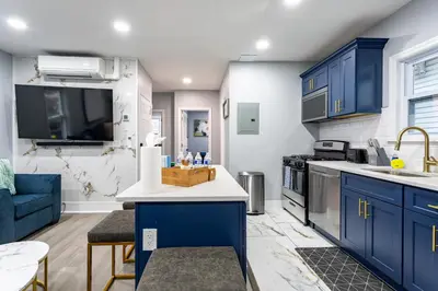 a kitchen with blue cabinets and a blue couch at Comfort Meets Style 3BR Plus Parking in New Rochelle