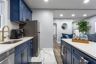 a kitchen with blue cabinets and a sink at Comfort Meets Style 3BR Plus Parking in New Rochelle