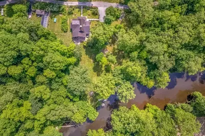 an aerial view of a house in the woods next to a river at Rose & Thorne in Gardiner