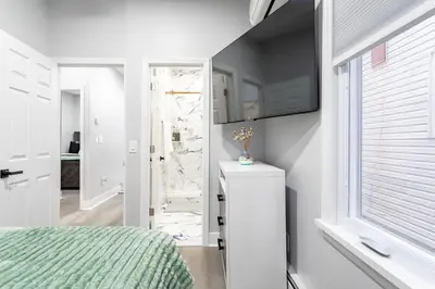 a white bedroom with a bed and a window at Modern Escape 3BR Apt with Parking in New Rochelle