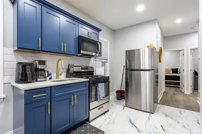 a kitchen with blue cabinets and a stainless steel refrigerator at Modern Escape 3BR Apt with Parking in New Rochelle