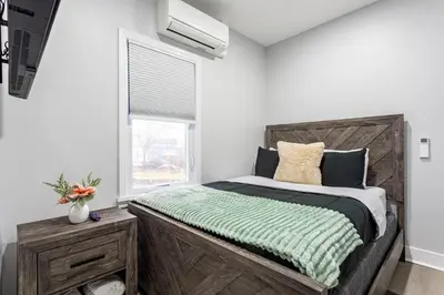 a bedroom with a large wooden bed with a window at Modern Escape 3BR Apt with Parking in New Rochelle