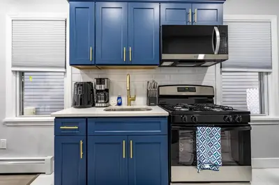 a blue kitchen with a stove and a microwave at Modern Escape 3BR Apt with Parking in New Rochelle