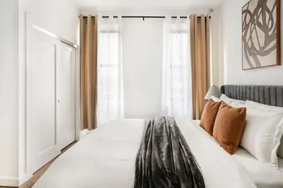 a bedroom with a large white bed with windows at 1290-10 New Renovated 2 Bedrooms in UES in New York