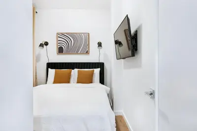 a white bedroom with a bed and a tv at 1290-10 New Renovated 2 Bedrooms in UES in New York