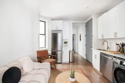 a white living room with a couch and a kitchen at 1290-10 New Renovated 2 Bedrooms in UES in New York