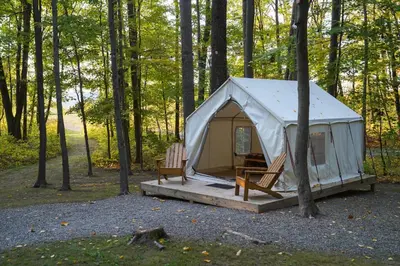 a tent with two chairs and a table in the woods at Heavens Landing at Moon Valley Campground in Vernon Township