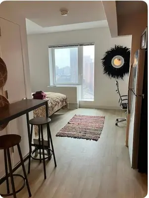 a living room with a bed and a table and a window at The Gilbert in New York