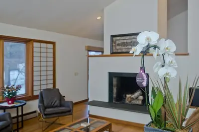 a living room with a fireplace and a chair at Amherst Woodland Escape in Amherst