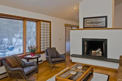 a living room with a fireplace and two chairs at Amherst Woodland Escape in Amherst