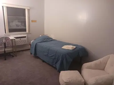 a bedroom with a bed and a chair and a window at Comfy Room in Fresh Meadows in Utopia