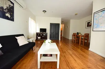 a living room with a black couch and a table at Great! Private NYC Room in Sunnyside in Haberman