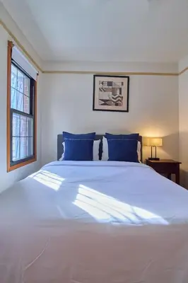 a bedroom with a large white bed with blue pillows at Sweet Home - Zoller Stays in Long Island City