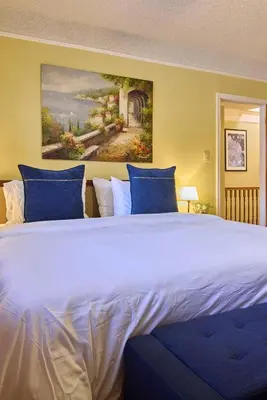 a large bed with blue pillows and a painting on the wall at Sweet Home - Zoller Stays in Long Island City
