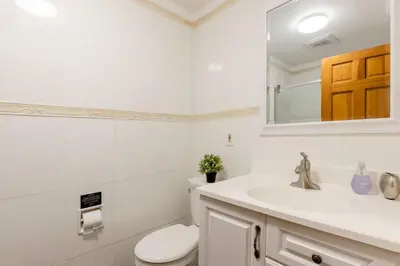 a white bathroom with a toilet and a sink at Sweet Home - Zoller Stays in Long Island City