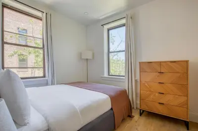 a white bedroom with a bed and two windows at Blueground E Village rooftop pool gym ac NYC-1533 in New York
