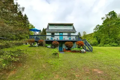 a large house with a balcony on a green field at Catskills Mountain Casita Ski, Hike, Fish and Golf! in Denver
