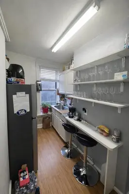 a kitchen with a refrigerator and a counter with bar stools at Next to Manhattan 2 Bedrooms Apartment - Subway 20 steps, Manhattan 1 Stop in Roosevelt Island