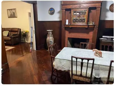 a living room with a table and a fireplace at Charming Victorian Home in the Heart of White Plains in White Plains