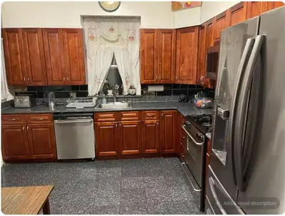 a kitchen with wooden cabinets and a stainless steel refrigerator at Charming Victorian Home in the Heart of White Plains in White Plains