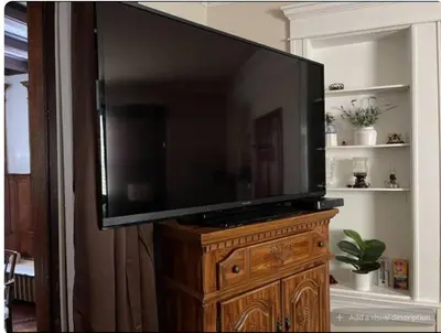 a large flat screen tv sitting on top of a wooden stand at Charming Victorian Home in the Heart of White Plains in White Plains