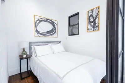 a bedroom with a white bed with three pictures on the wall at 69-5C Festive Comfort Brand New 1BR Lower East Side Christmas Ready in New York
