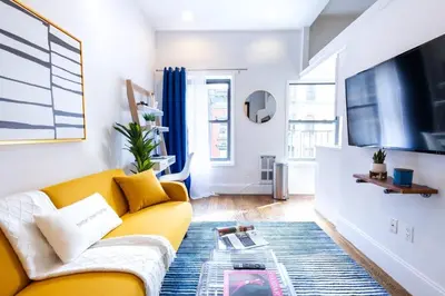 a living room with a yellow couch and a tv at 69-5C Festive Comfort Brand New 1BR Lower East Side Christmas Ready in New York