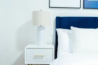 a white nightstand with a lamp on it next to a bed at 49-3B Newly renovated 2BR WD Midtown East in New York