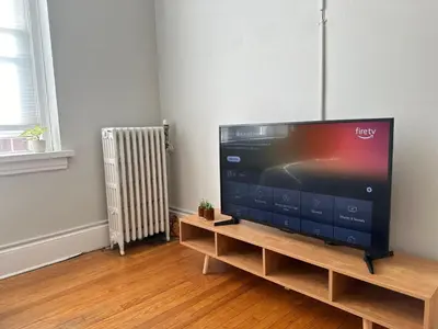 a flat screen tv sitting on a stand in a living room at Serene Nordic Escape Close to Yale in New Haven