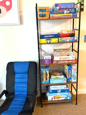 a book shelf filled with books next to a stack of books at Game Night Suite at Jiminy Peak Ski OnOff Sleeps 4 in Hancock