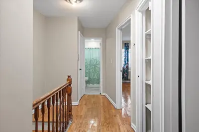 a hallway with white walls and a staircase with wood floors at Uptown Escape in Mount Vernon