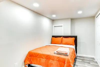 a bedroom with an orange bed in a white room at 14 Mi to Central Park Chic Mt Vernon Retreat in Vernon Park