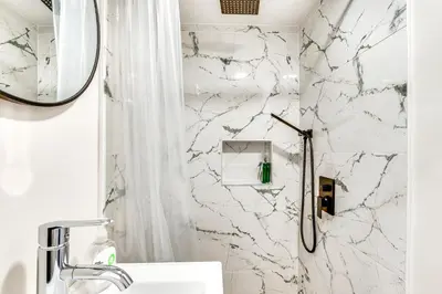 a white bathroom with a marble wall at 14 Mi to Central Park Chic Mt Vernon Retreat in Vernon Park