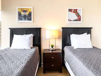 a bedroom with two beds and a table with a lamp at Luxury Apt with Gym Downtown in Stamford