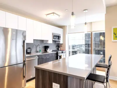 a kitchen with white cabinets and a stainless steel refrigerator at Luxury Apt with Gym Downtown in Stamford