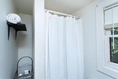 a white shower curtain in a bathroom next to a window at Saratoga Cabins in Malta