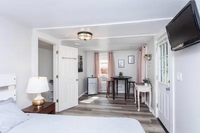 a white bedroom with a bed and a table at Saratoga Cabins in Malta