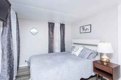 a white bedroom with a bed and a table with a lamp at Saratoga Cabins in Malta