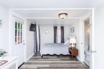 a white bedroom with a bed and a bathroom at Saratoga Cabins in Malta