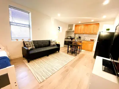 a living room with a black couch and a kitchen at Rayhaan Palace in Long Island City