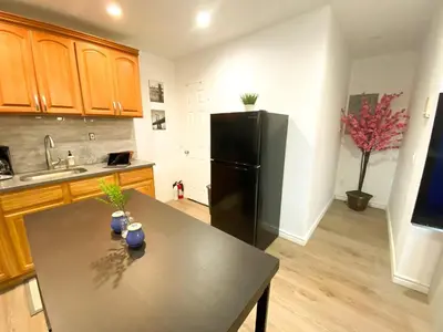 a kitchen with a black refrigerator and a table at Rayhaan Palace in Long Island City